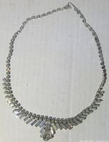 Full view of the rhinestone necklace showing the flared design and silver-tone chain with linked rhinestones.