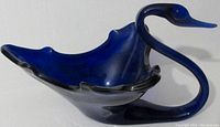 Side angle view of the large blue glass swan showing curved neck, beak details, and wing-shaped bowl body.