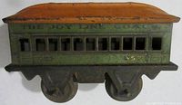Side view of the Girard Joy Line Coach showing the green metal body with orange roof and painted 'THE JOY LINE 357'. Shows wear and paint loss consistent with age.