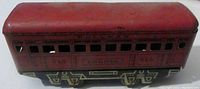 View of the opposite side of the vintage red tin litho MARX O Gauge Bogota 245 Pullman passenger car showing window cutouts, printed text, and lithograph details on wheels and base.