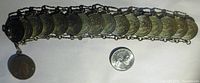 Full view of the bracelet laid out flat showing all linked 5 centavo coins with an additional hanging coin and a US dime for size comparison.