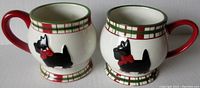 Pair of ceramic Scotty dog mugs showing front side with black dogs wearing red bows, plaid border near rim and base, red handles