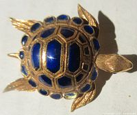 Top view of the turtle pin showing the royal blue enamel segments on the gold shell with detailed gold legs, head, and tail.