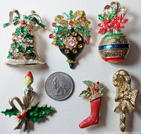 Six Christmas pins arranged around a US quarter for size reference.