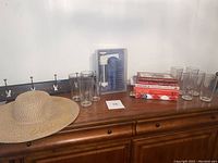 Full lot on wooden surface showing all included items: cookie press, cookbooks, water glasses, coat rack, and hat.