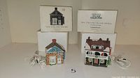 Overview of four Dept 56 New England Village figurines with original boxes and power cords visible.
