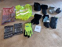 Overview of all items: gloves, head wraps, reflective vest, hat, and ear muffs arranged on carpet