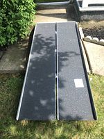 Photo showing top side of the folded ramp with textured non-slip surface and metal edges.