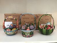 Three Jim Shore decorative baskets with assorted hand-painted eggs visible inside, arranged side by side with original boxes in the background.