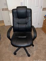 Front view of black office chair showing padded faux leather seat and backrest with stitched design, plastic armrests, and five caster wheels