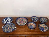 Set of 7 ceramic pieces including pie dish, bowls, and plate arranged on wooden surface showing the collection from front.