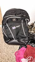 Black TCU branded backpack with reflective strips on carpet with leopard print tote visible