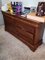 Full view of the dresser showing six drawers and dark brown wood finish with items on top.