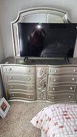 Full view of dresser and mirror with TV on top, showing goldtone finish and mirrored center panel