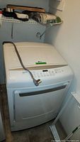 Full view of white LG dryer with power cord on top