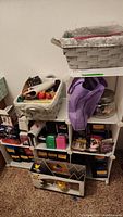 Overall view of collapsible shelf unit with baskets, jar of dice, jewelry bag, resin figurine, and Pokémon boxes