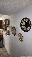 Photo showing 7 woven baskets mounted on the wall in a hallway, featuring various sizes and black and natural fiber patterns.