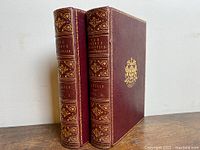 Two volumes front cover view showing burgundy leather covers and gilt crest plate