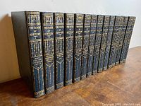 Side view of the 15 volume book set showing dark blue hardcovers with gold embossed spines