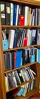 Four-tier wooden shelving unit filled with binders and reports