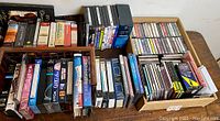 Full overview of all physical media showing VHS tapes, cassettes, CDs, and DVDs arranged on a wooden table