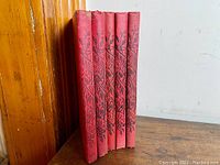 Five red cloth hardcover Vermot Almanac books standing upright side by side showing spines with black stamped floral design and title.