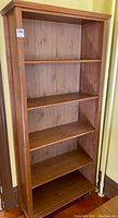 Full view of the solid pine wood bookcase showing all five shelves, wood grain, and general condition.