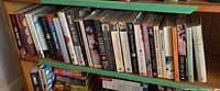 Shelf of assorted paperback books with varied titles including thriller and fiction genres.