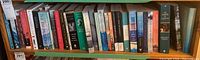 Full view of bookshelf with 22 assorted paperback books of different authors and styles.