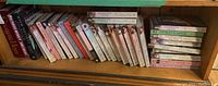 Shelf with about 30 Georgette Heyer novels, mainly vintage editions in paperback and hardcover with various illustrated and photographic dust jackets.