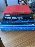 Stack of 5 books stacked on a wooden table, titles clearly visible.