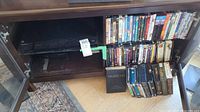 Sony Blu-ray and DVD player unit in a wooden shelf with multiple DVD and Blu-ray discs on the same shelf and beside it.