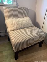 Front view of the extra wide upholstered chair with striped fabric and white fluffy pillow
