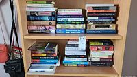 Shelf showing multiple stacks of books with a variety of titles and genres.