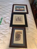 Three framed art prints laid on a bed showing overall size and frames