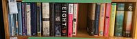 Photo of one shelf of hardcover books showing a variety of novels and historical works.