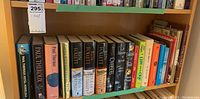 Shelf with a variety of hardcover books showing spines and titles.