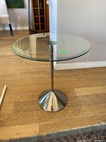 Side view of the glass top side table showing the metal base and glass surface