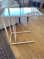 Side view of the white metal frame and glass top sofa table showing the structure and base design.