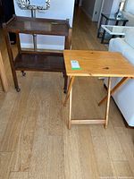 Photo showing both tea trolly and folding side table on hardwood floor with visible wear on the trolly surface.