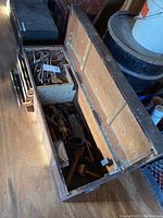 Open antique wooden tool box showing assorted hand tools inside including wrenches and bits