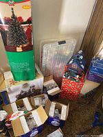 Photo showing fiber optic tree box labeled Yule Time 48-inch lighted tree, other boxes of decorations including Santa figurine and lighted houses.