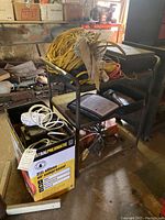 Photo showing Central Pneumatic 3 gallon air compressor box next to metal utility cart with cords on it