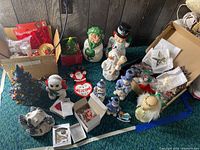 Full assortment of holiday decorations including ceramic snowmen, light-up ceramic Christmas tree, Santa welcome sign, and various other Christmas-themed ornaments and bows.