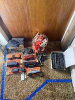 Overview of boxed Lionel locomotives and rolling stock with box of curved tracks and plastic buildings
