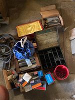 Wide view showing various hardware items including nails, small boxes, storage compartments, and a blue bag.