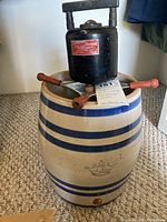 Side view of the three gallon stoneware crock with blue stripes and crown emblem, topped with the Heidolph emulsion mixer showing wooden handles
