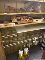 Shelved kitchen items including Pyrex Bake A Round box, metal multi-tier oven rack, canning support, and two push button coffee thermoses in cardboard boxes below shelving