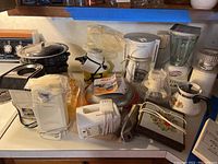 Overview of the lot on a kitchen countertop with stove in background, showing all small appliances and cookware included in the lot.