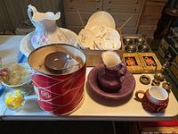 Wide-angle photo showing most ceramic and glass items on a table, including wash pitcher and bowl set, Blue Ridge plates, side bowls, trays and coaster set in boxes.